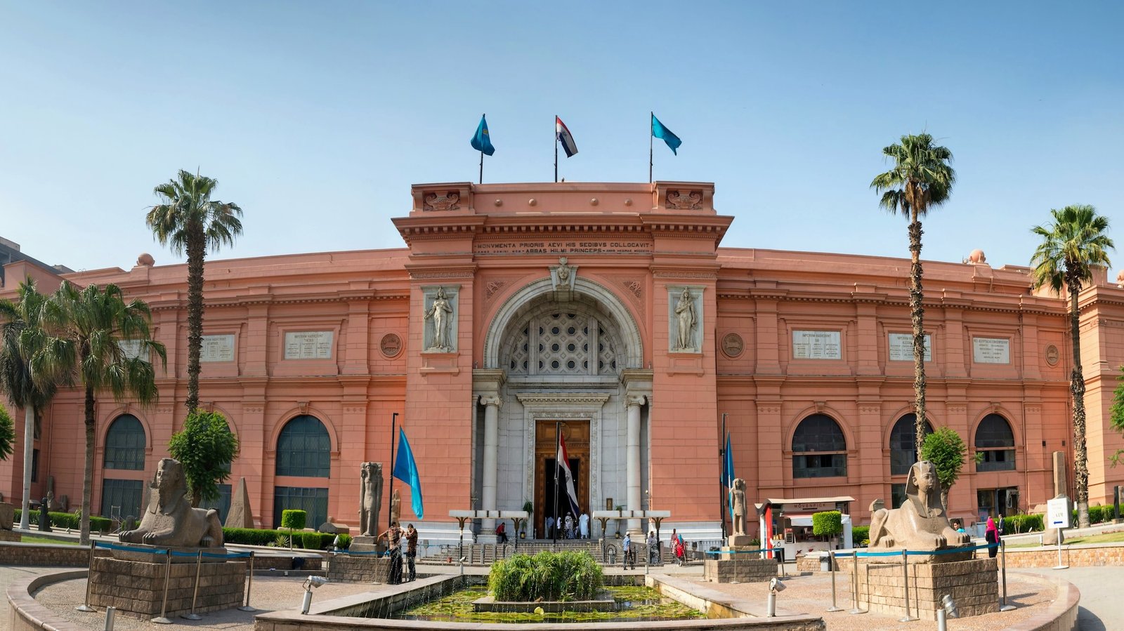 Turistas visitando el Museo Egipcio de El Cairo con palmeras y estatuas